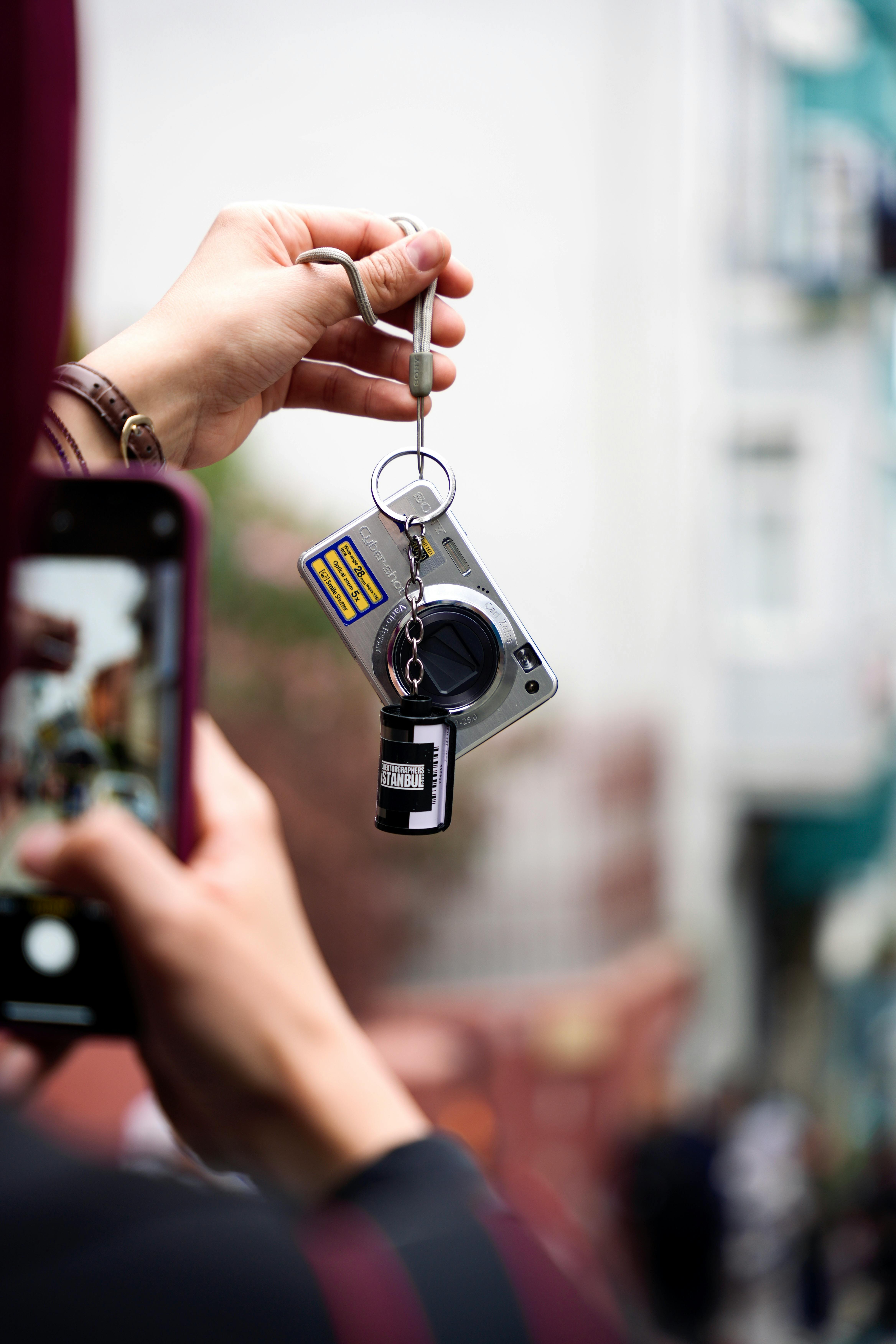 A person holding a smartphone captures a unique keychain with a lens design.