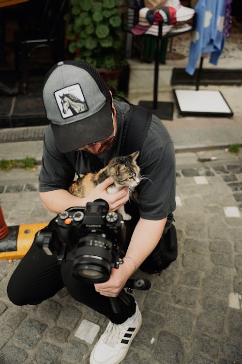 Man with Camera Holding Kitten on Street