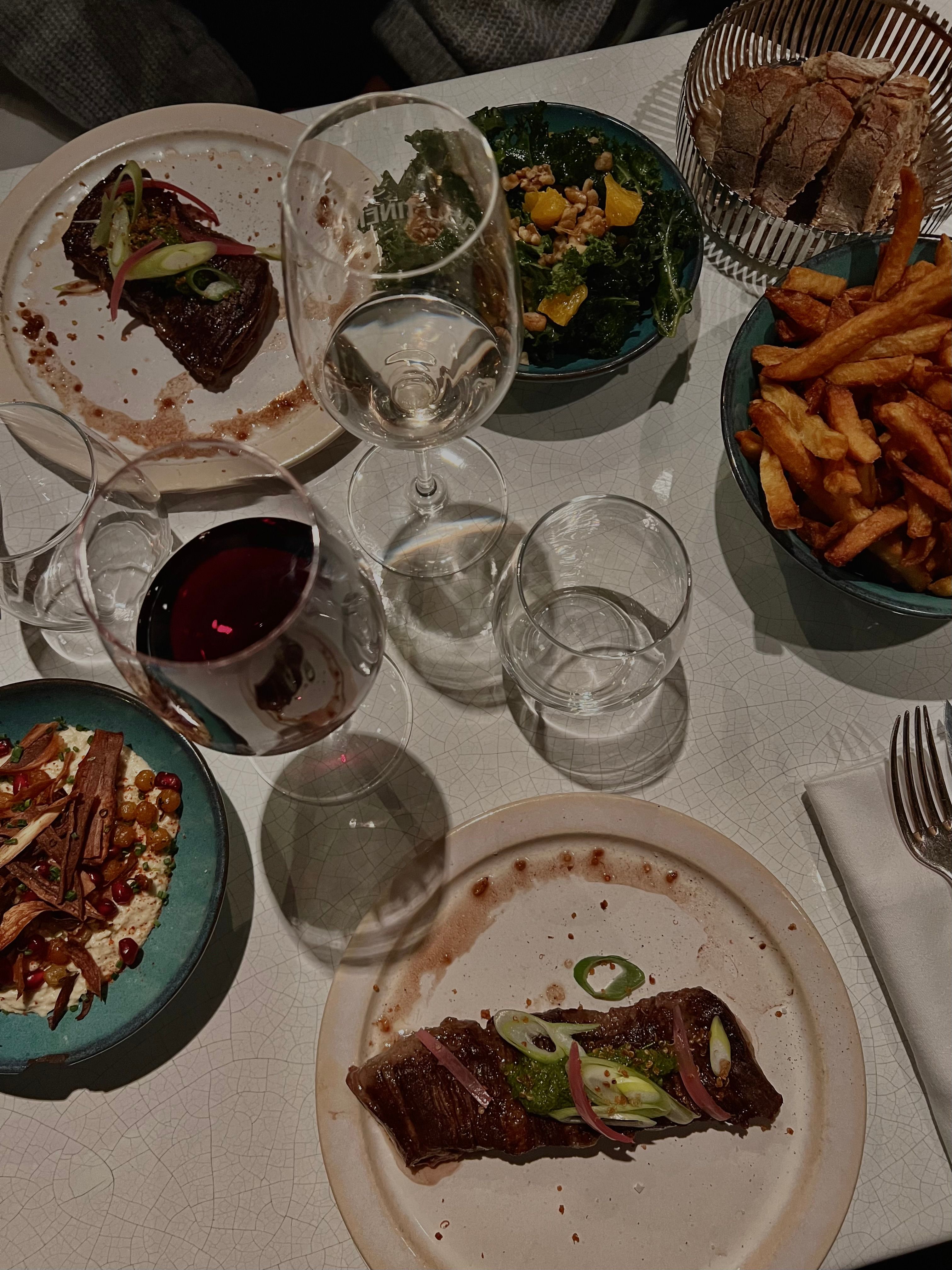 Elegant dining setup with gourmet meal, wine, and sides at a restaurant.