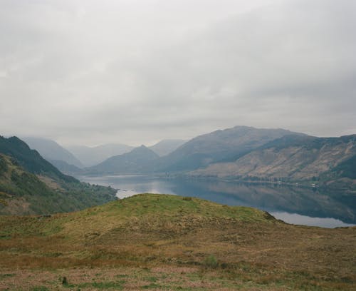 A view of a lake and mountains from a grassy hill