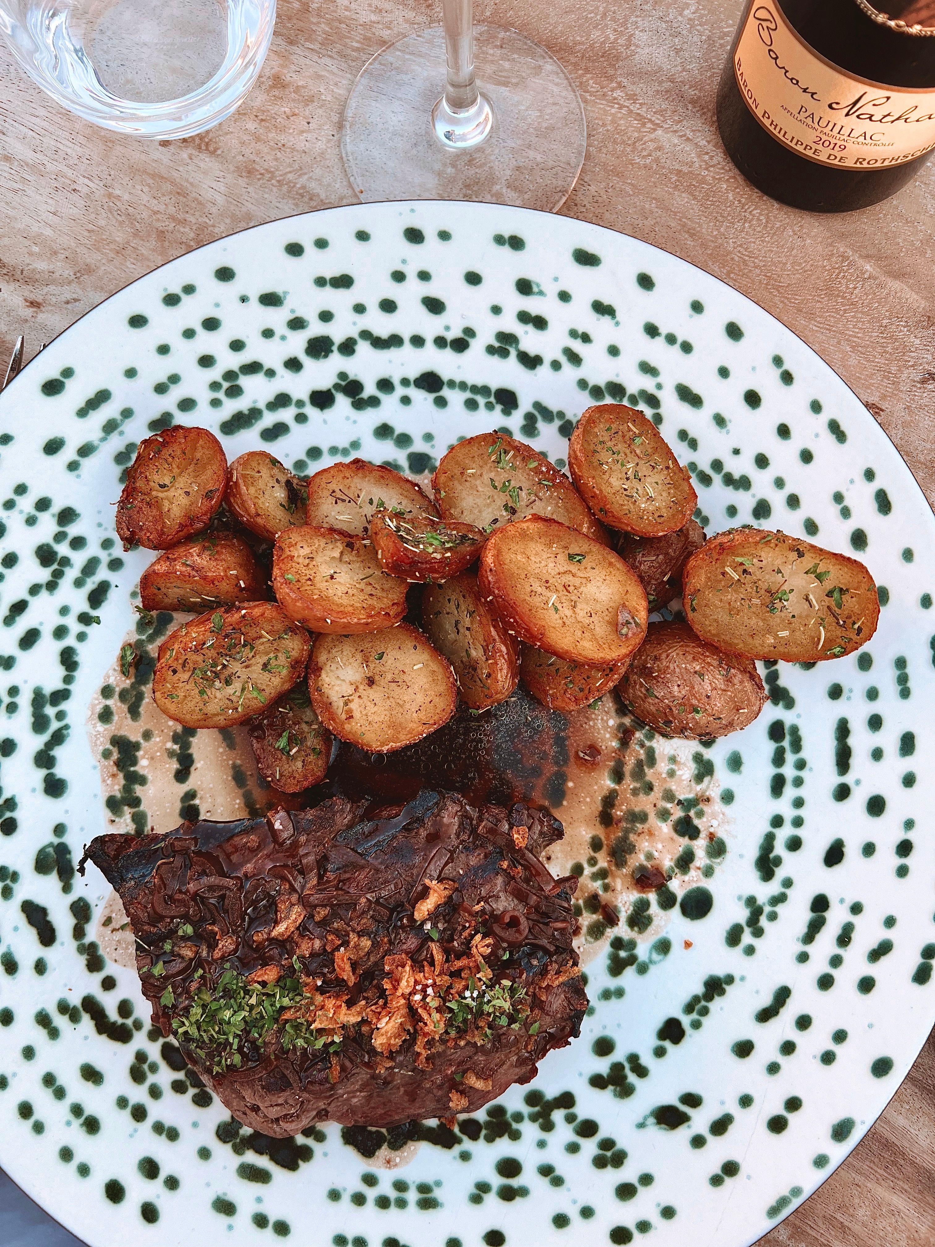 Pommes de terre rôties aux herbes et viande braisée dans son jus, sur une assiette mouchetée de vert
