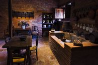 Cozy vintage kitchen with brick walls, wooden tables, and floral decor, creating a warm rustic atmosphere.