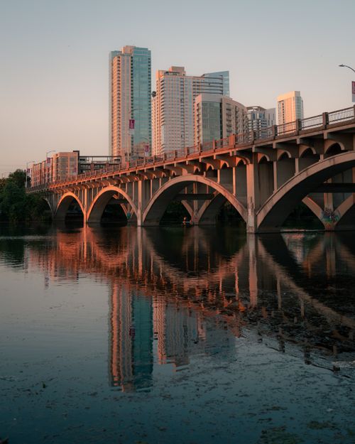 Free Stunning view of Austin's skyline with the Lamar Boulevard Bridge reflecting in Lady Bird Lake at sunset. Stock Photo