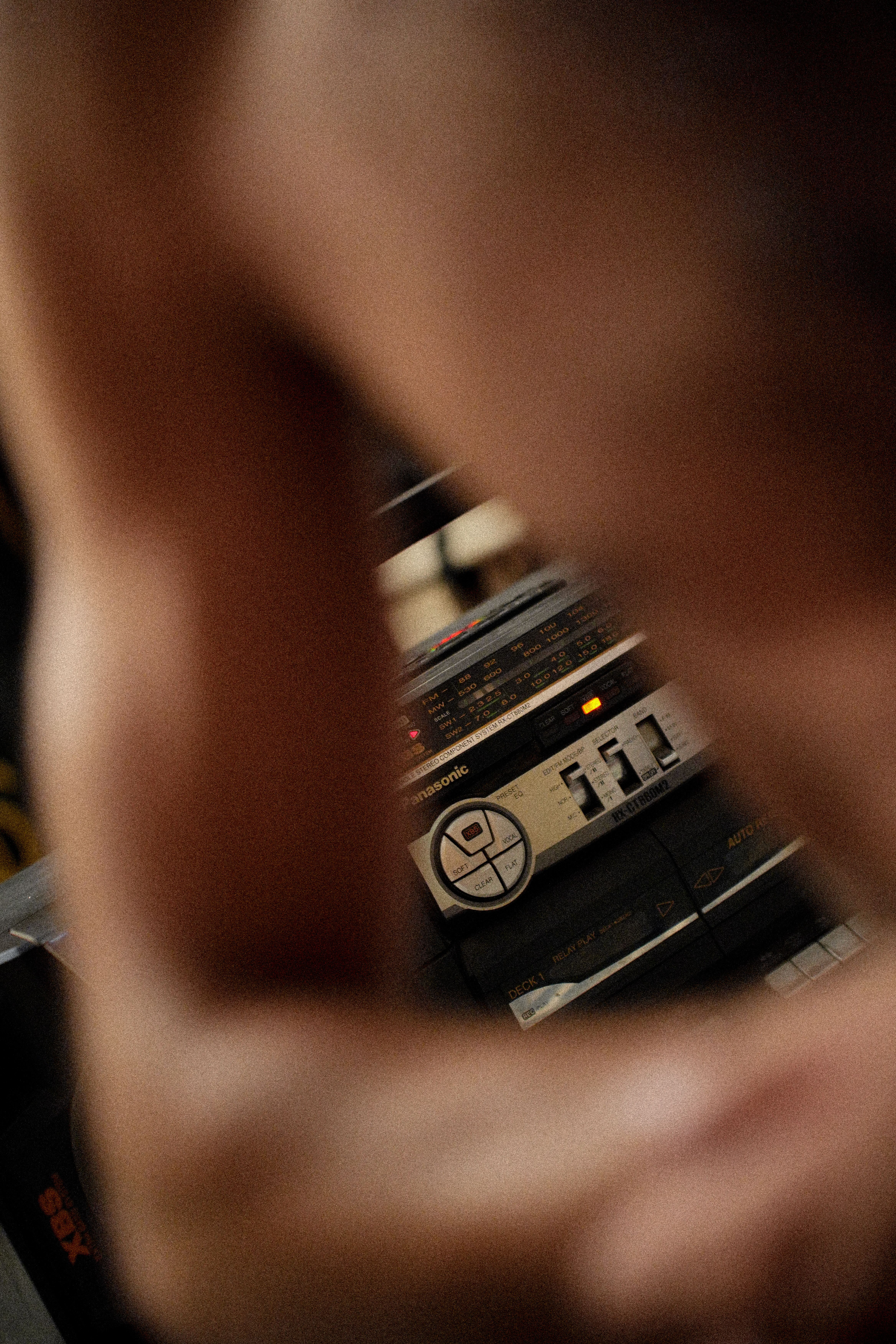 A shirtless man in front of an old-fashioned boombox with selective focus.