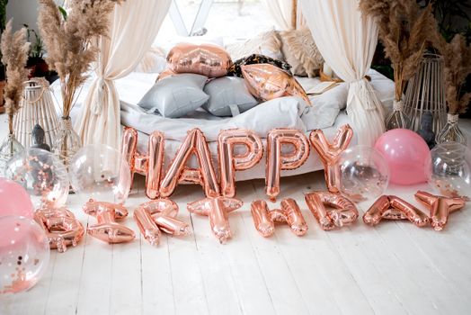 Stylish birthday setup with rose gold balloons and cozy decor in an indoor setting.