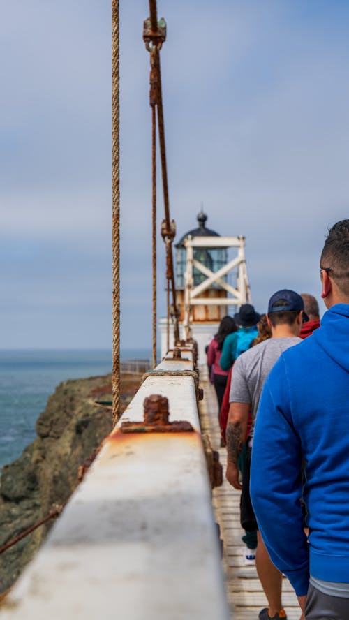 People standing on a bridge looking at the ocean