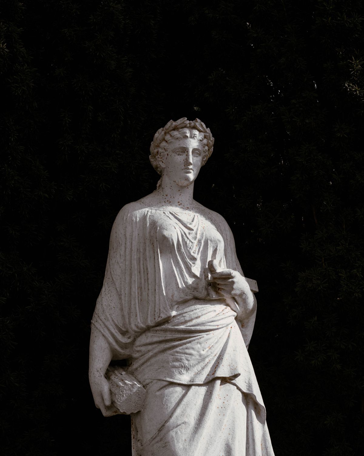 Classical marble statue of a draped woman against a dark background