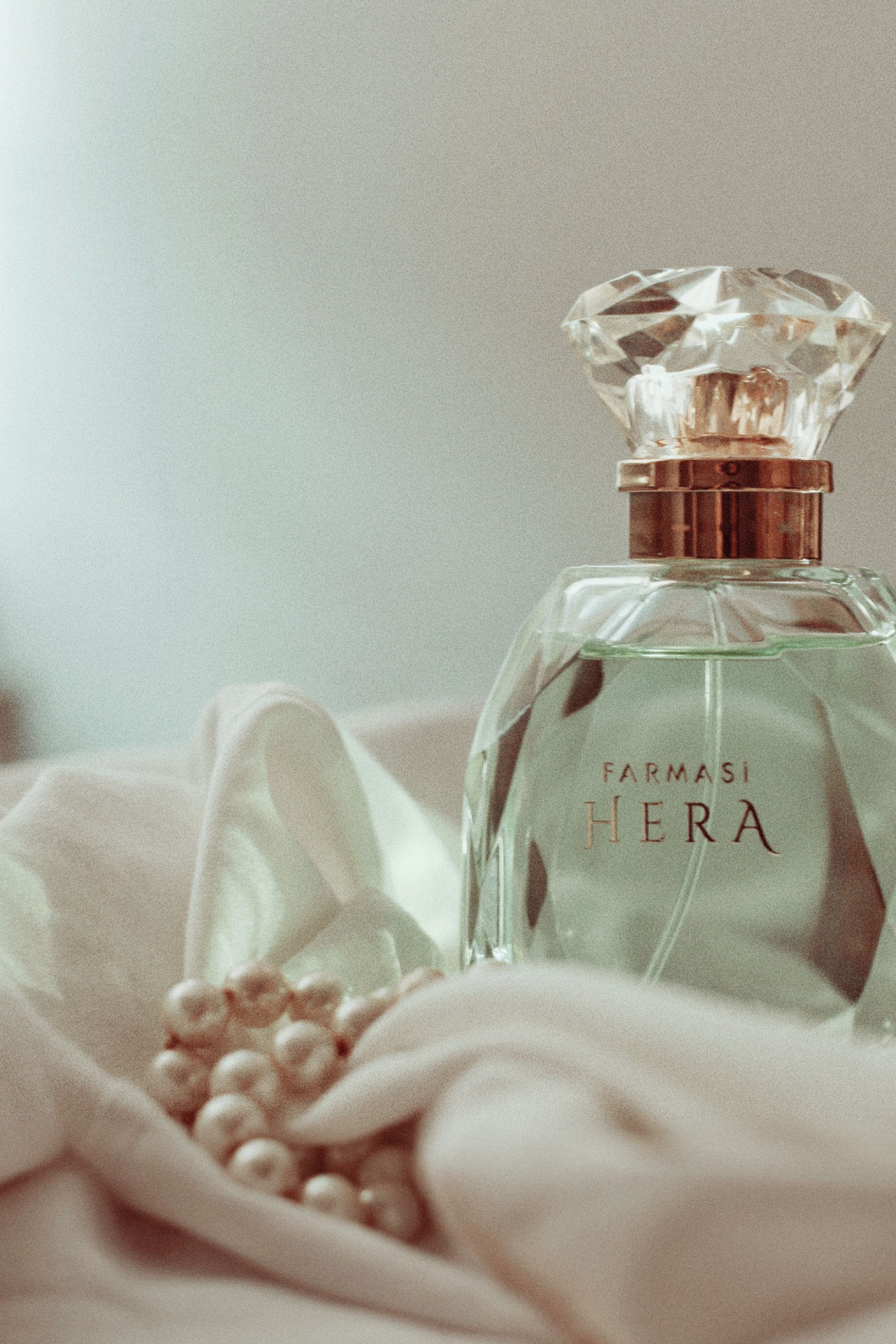 An elegant perfume bottle with pearls on a soft fabric, perfect for luxury branding.
