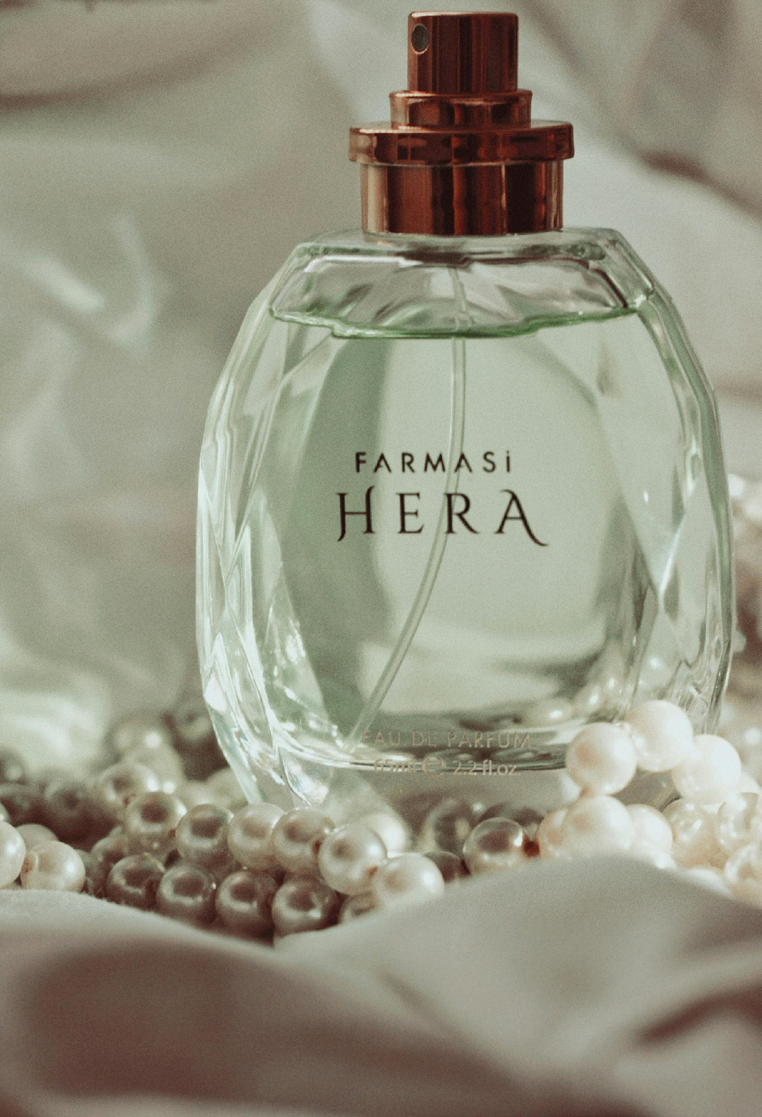 A stylish glass perfume bottle with pearls on a soft, delicate fabric background. Perfect for luxury and fashion themes.
