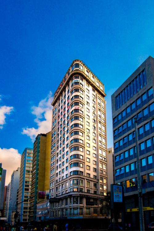 Free Stunning view of a tall urban building against a vibrant blue sky, capturing city architecture. Stock Photo