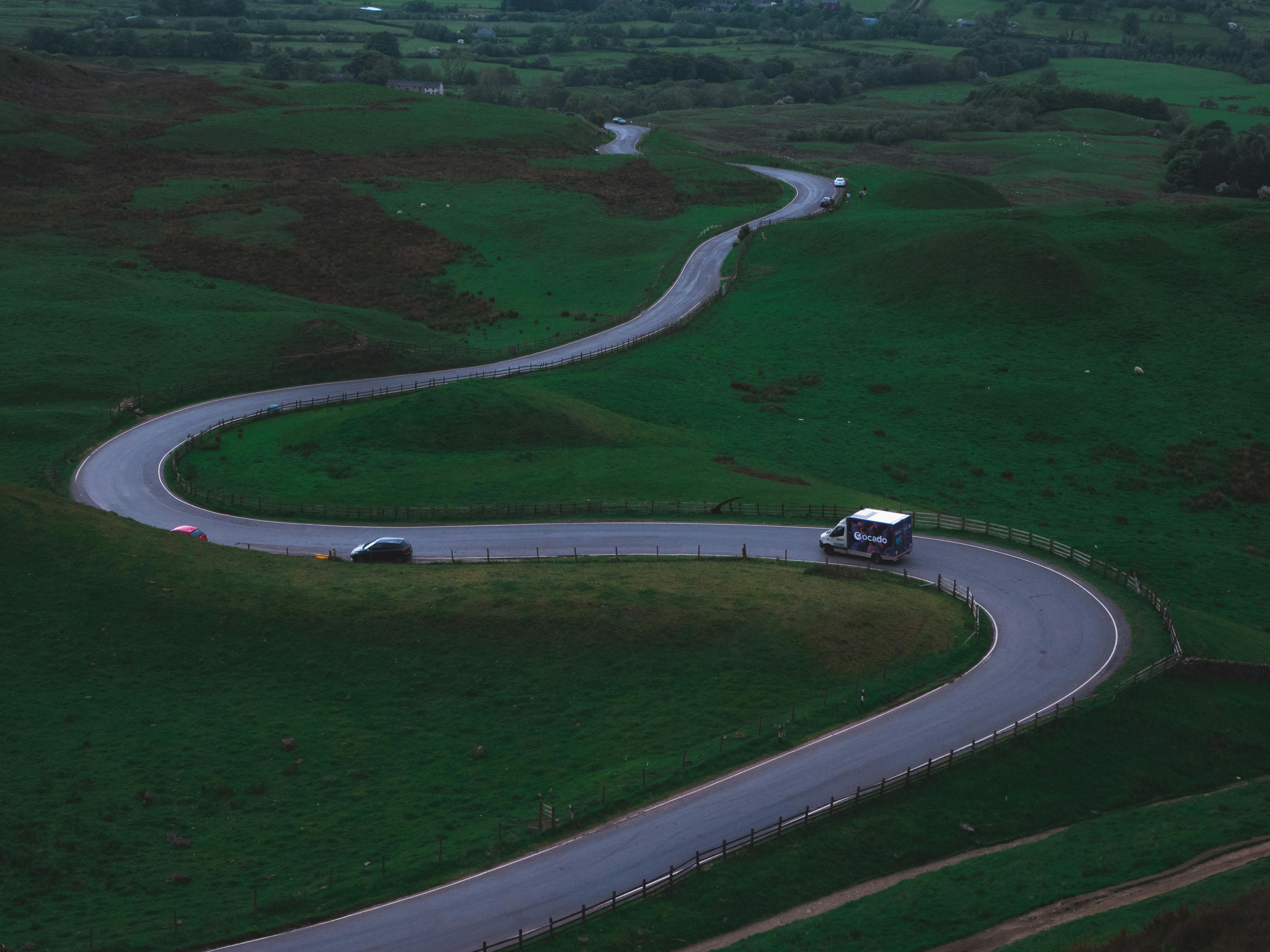 A road winding through the countryside with a car driving on it