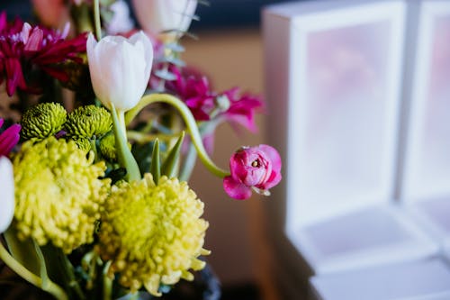 A bouquet of flowers in a vase with a white box