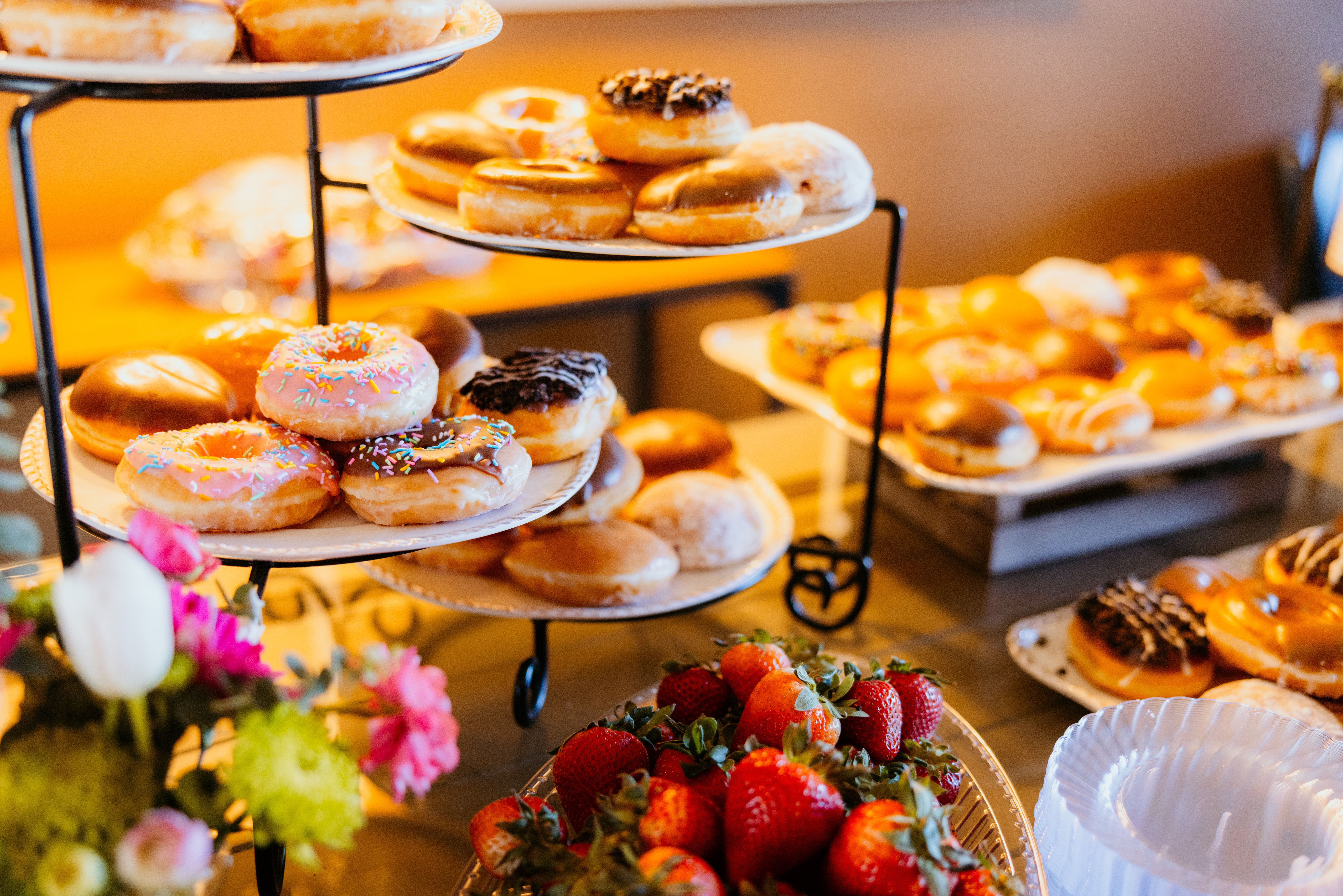 Vibrant assortment of doughnuts and fresh strawberries arranged on trays and plates.