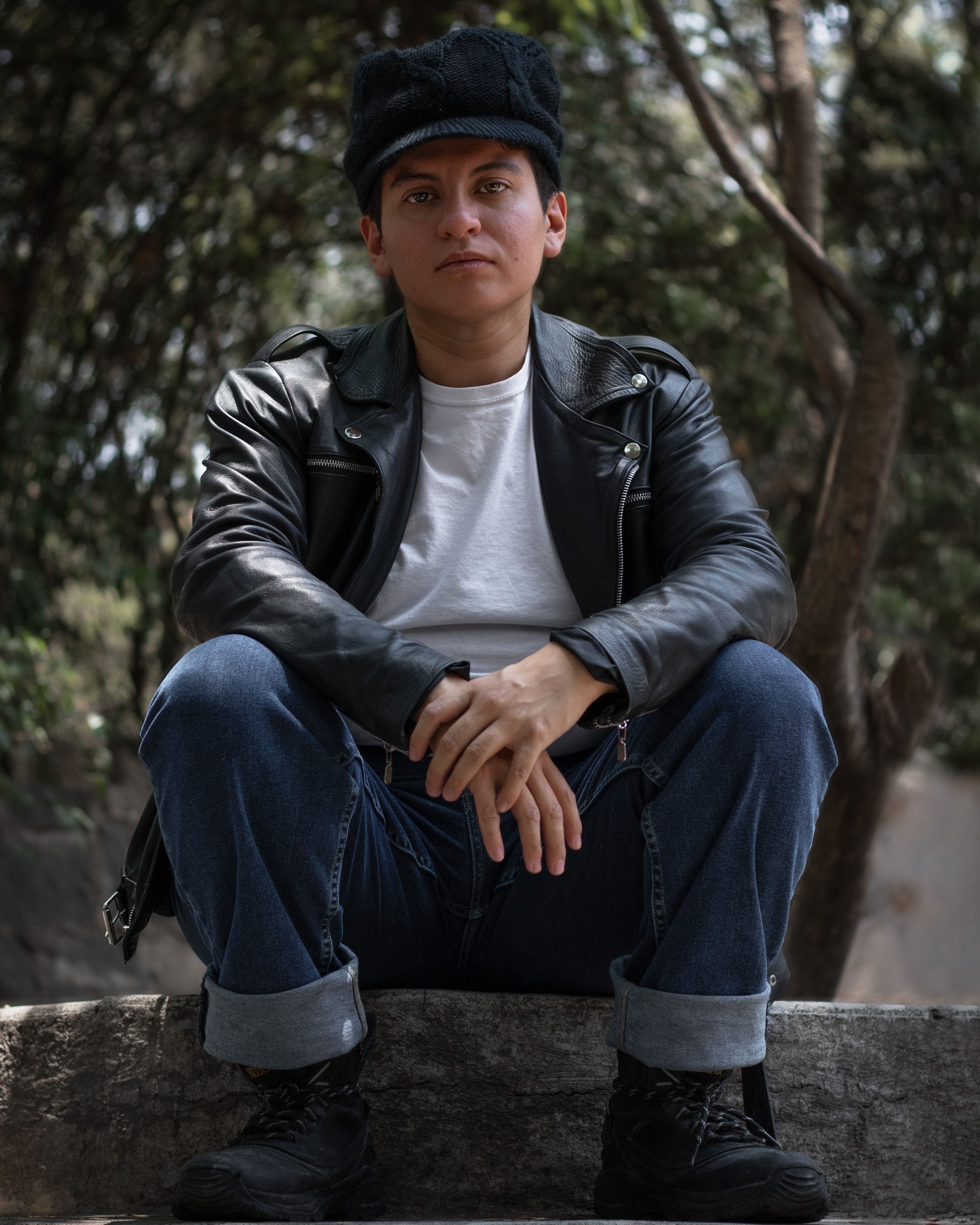 Stylish portrait of a man in leather jacket sitting in a park, Ciudad de México.