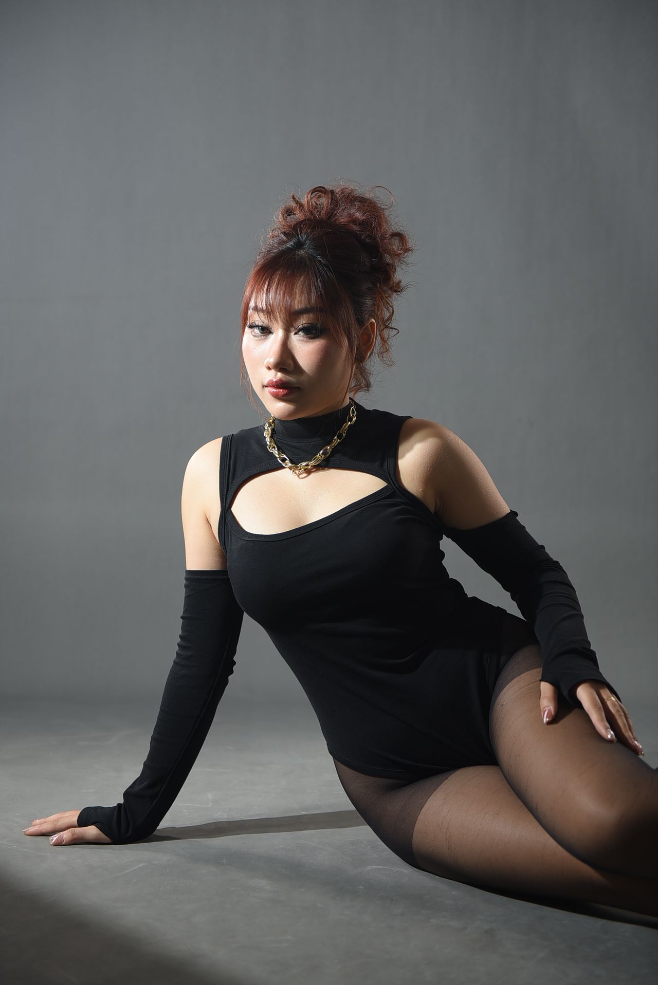 Woman in a black dress with sheer black tights, seated studio portrait