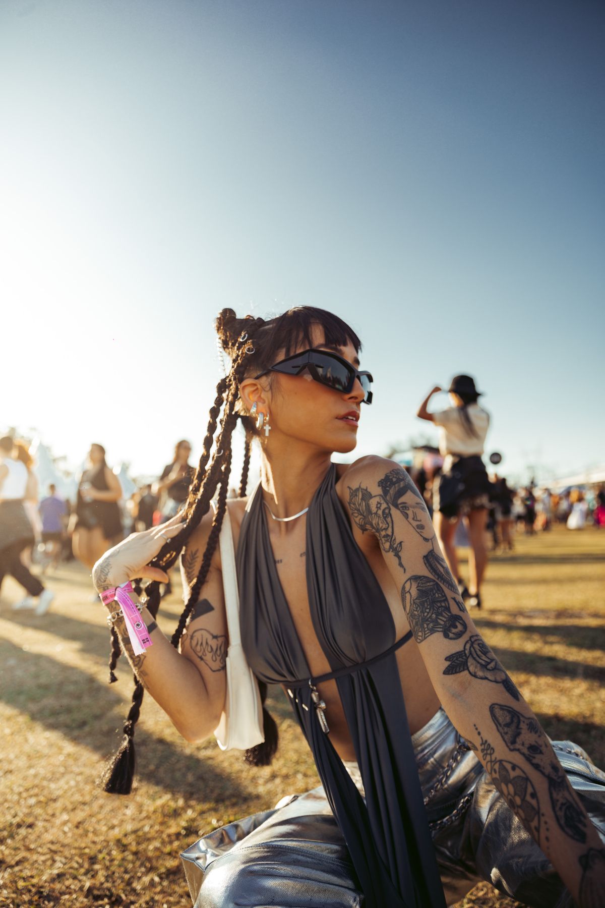 Woman with braids posing on festival grass in a bold concert outfit Woman with braids posing on festival grass in a bold concert outfit