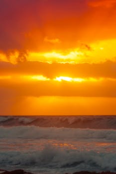 Stunning sunset over Akumal Beach with vibrant orange sky and crashing waves, perfect for serene ocean views.