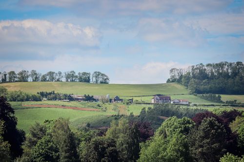 Free Picturesque rural landscape in Burton, UK with lush green fields and farmhouses under blue skies. Stock Photo
