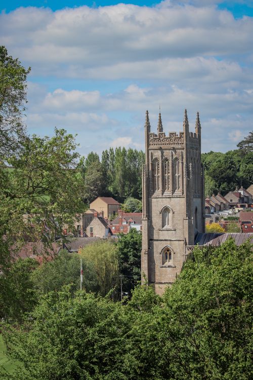 Free A stunning view of a Gothic church tower amidst lush greenery in Burton, England. Stock Photo