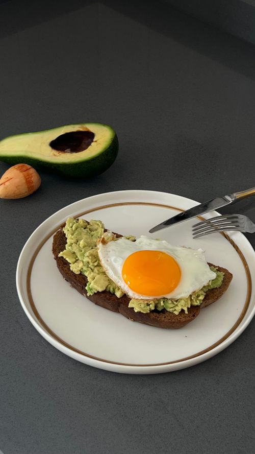 Free Delicious avocado toast topped with a sunny side-up egg, perfect for breakfast. Stock Photo
