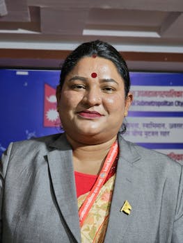 Close-up of smiling woman in professional attire with bindi, captured in a formal setting.