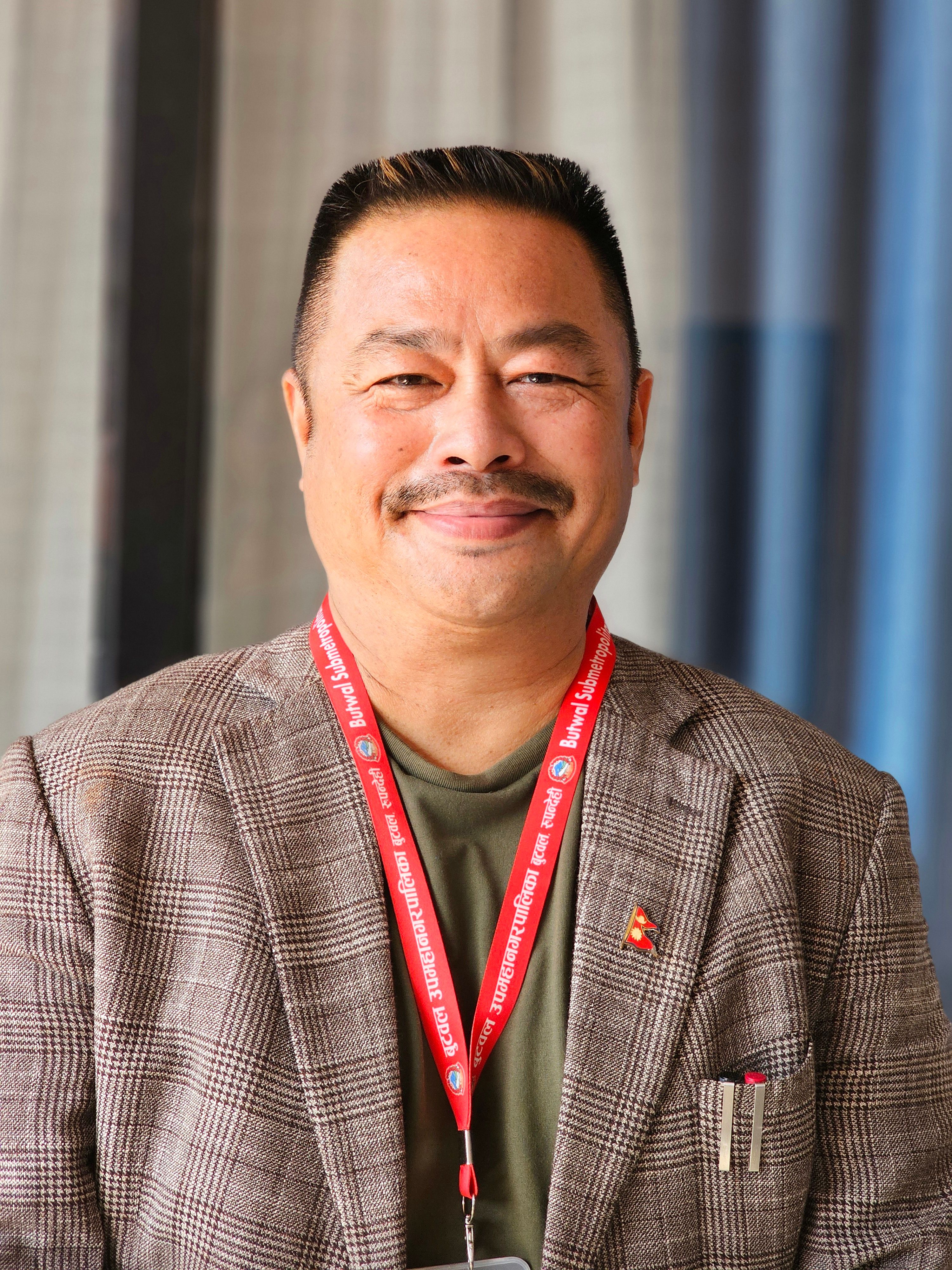 Cheerful middle-aged businessman smiling confidently wearing a suit and ID badge.