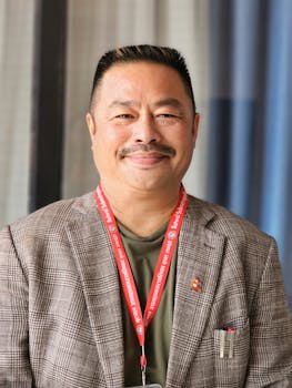 Cheerful middle-aged businessman smiling confidently wearing a suit and ID badge.