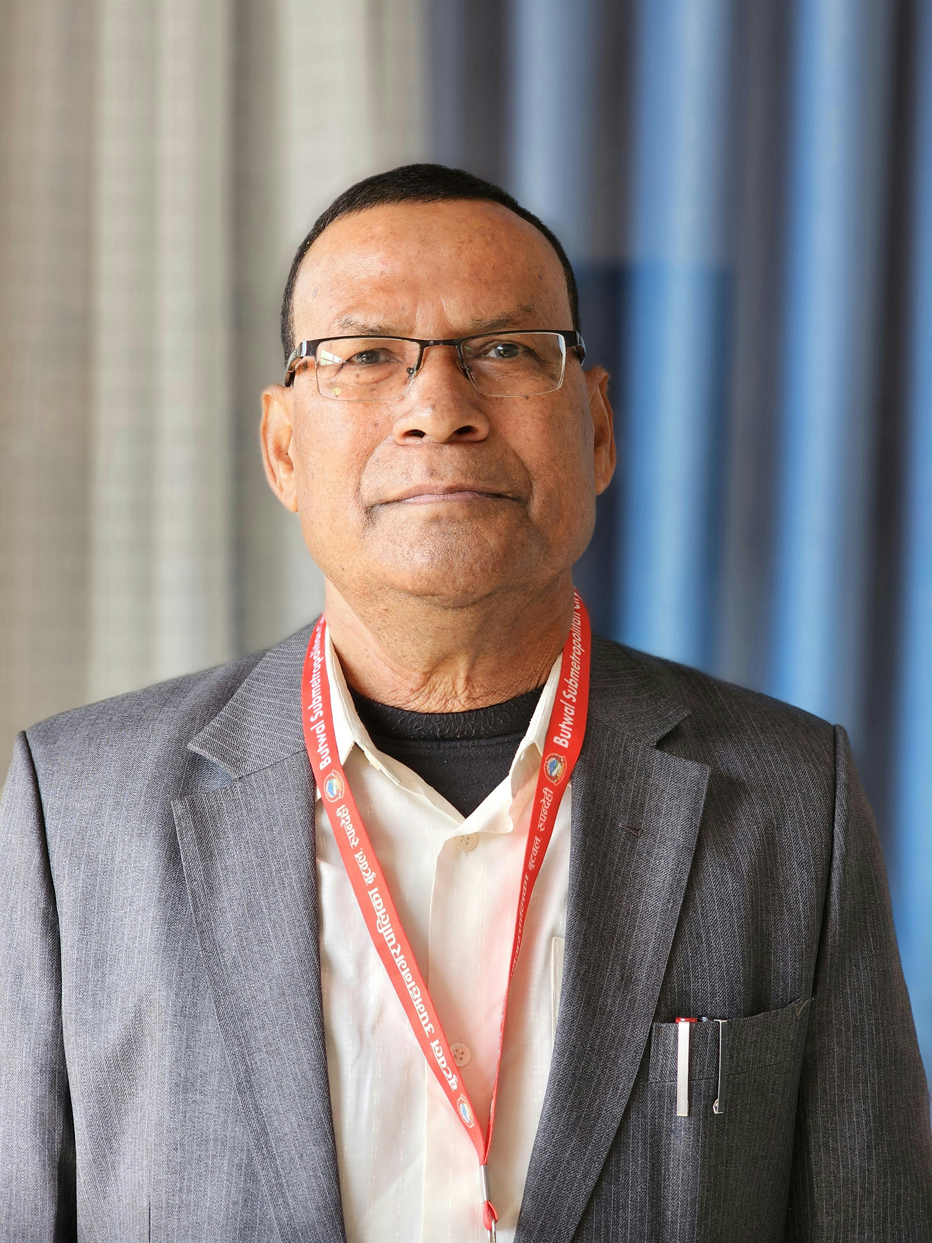 Portrait of a confident middle-aged man with glasses and a gray jacket, indoors.