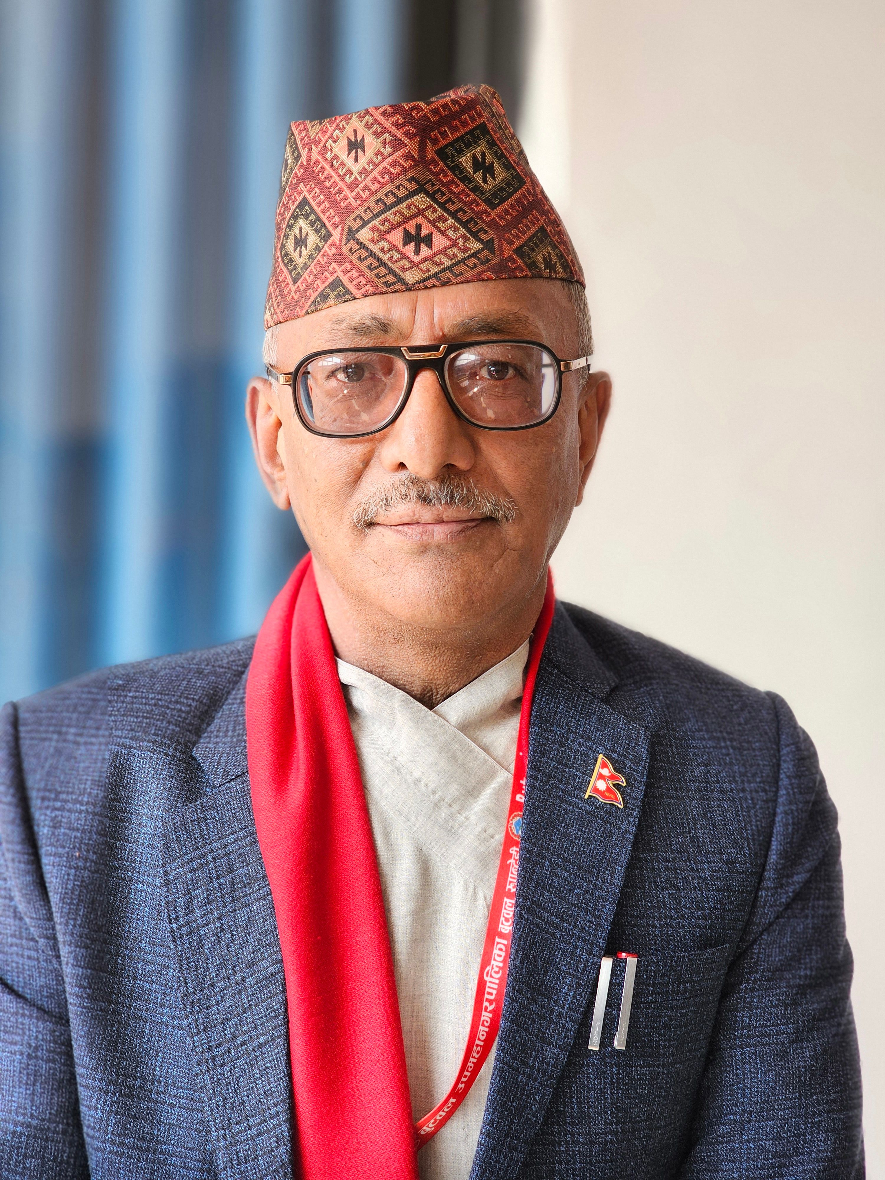 Elegant portrait of a man in traditional Nepali attire with glasses and mustache.