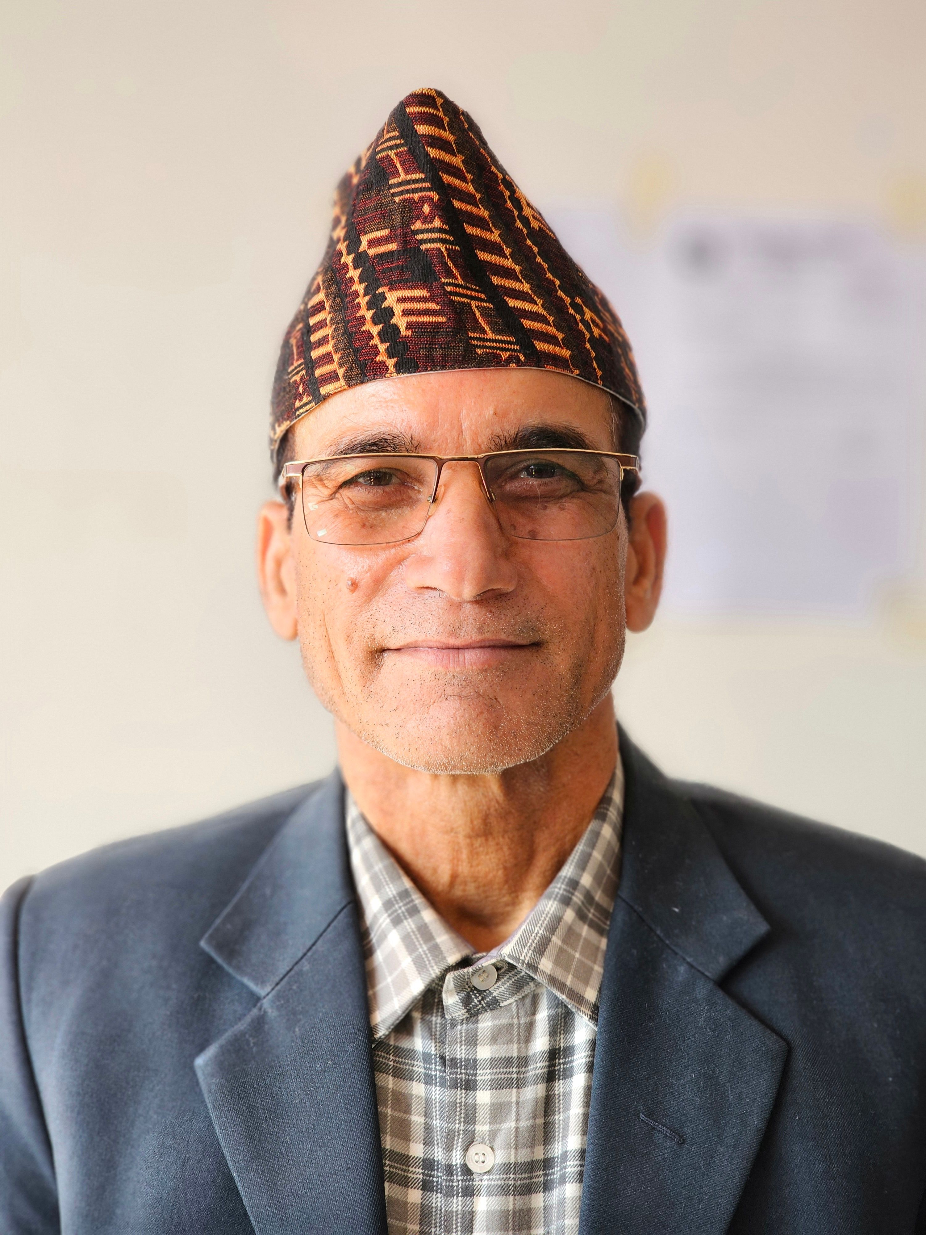 Portrait of an elderly man in glasses and traditional cap, exuding wisdom and warmth.