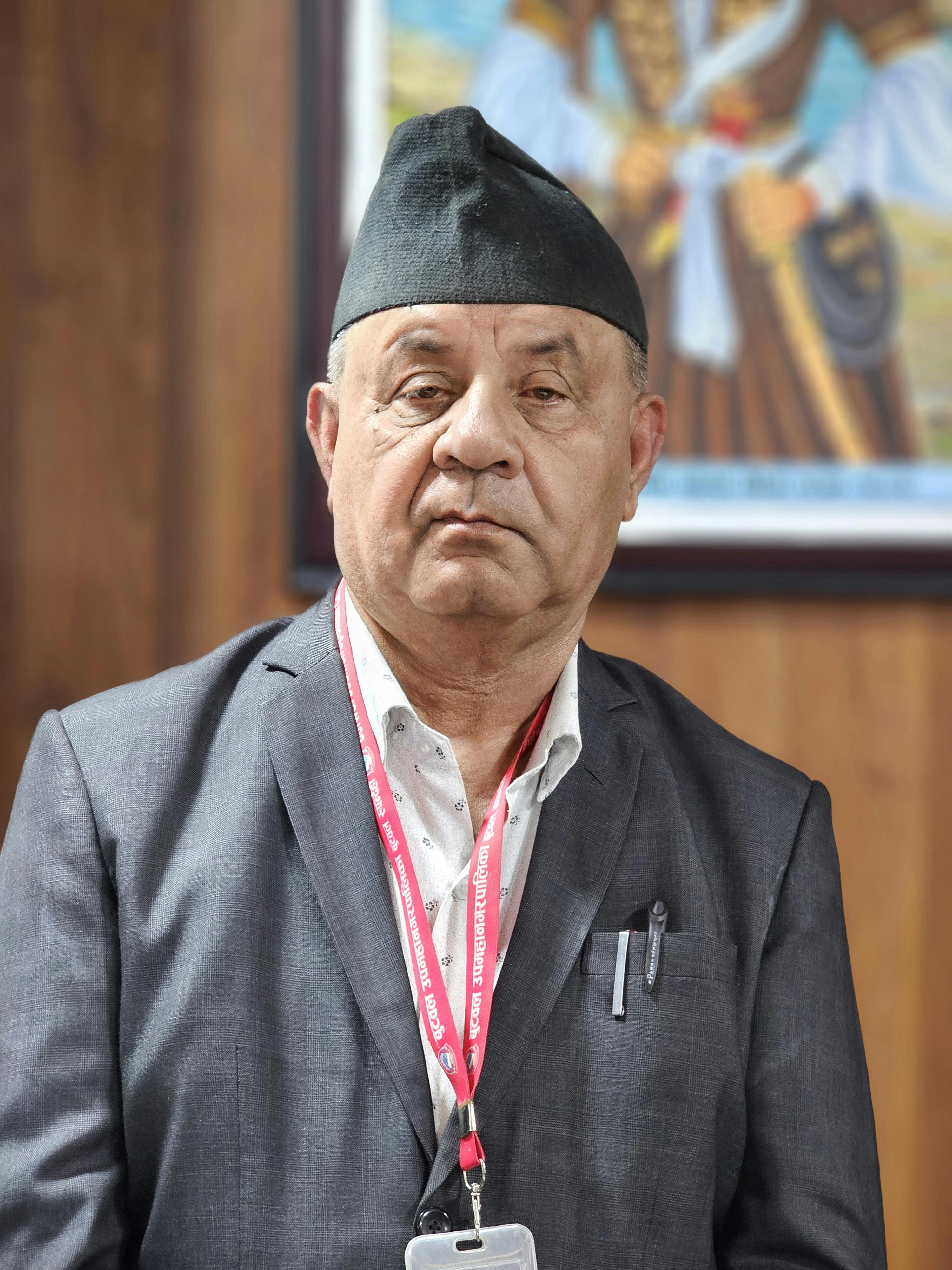 Portrait of an elderly man wearing a suit and traditional cap, presenting a composed demeanor.
