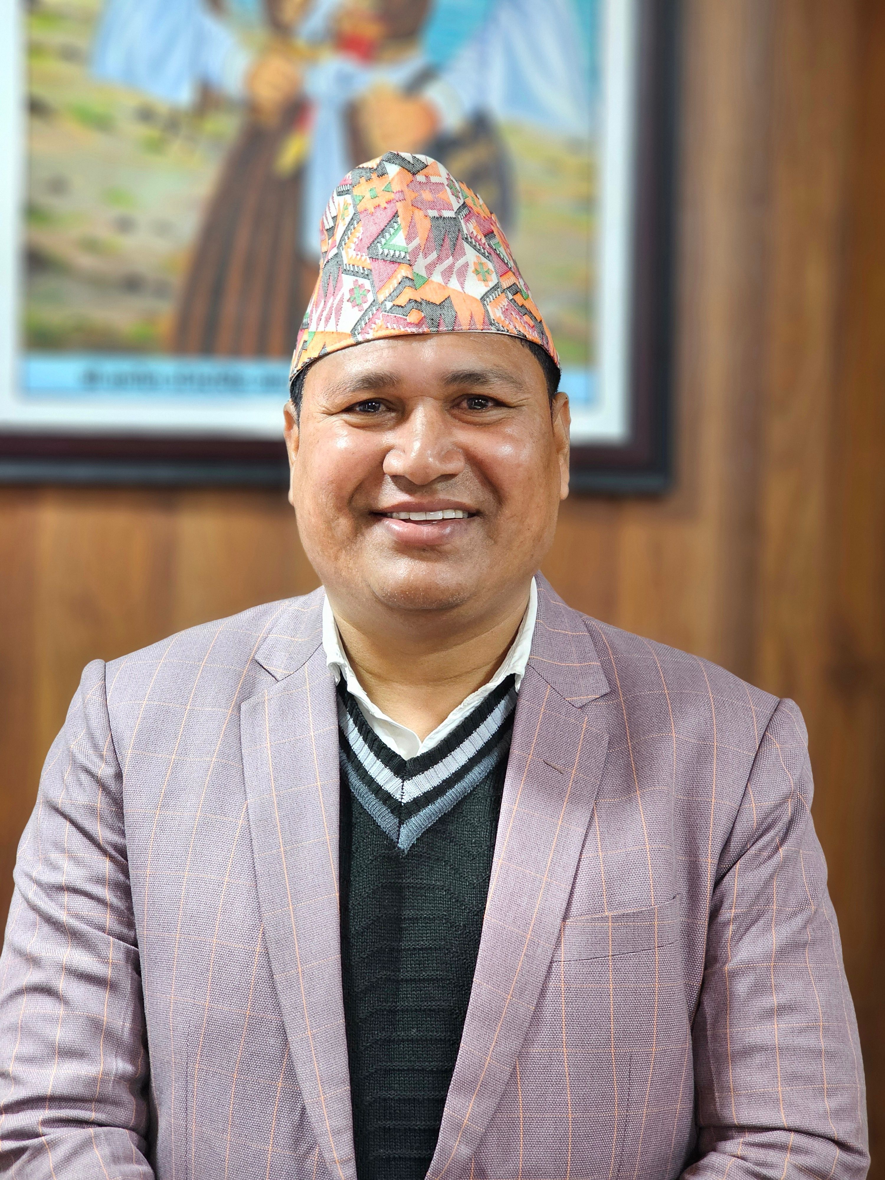 Close-up portrait of a smiling man wearing a traditional hat, dressed in a suit indoors.