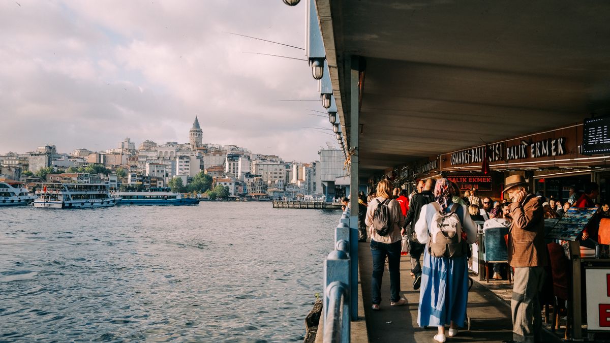 Bustling scene at Istanbul's Galata Bridge with Galata Tower in the background and bustling waterfront activities.