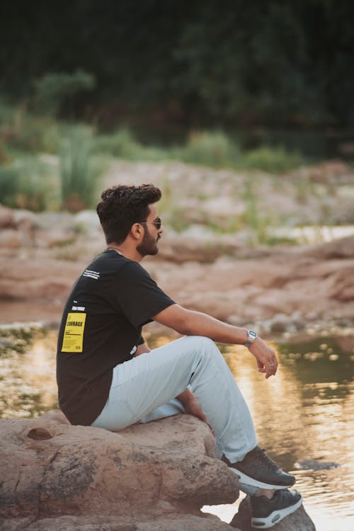 A man sitting on a rock in front of a river