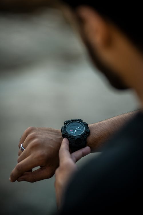 A man is holding a black watch on his wrist