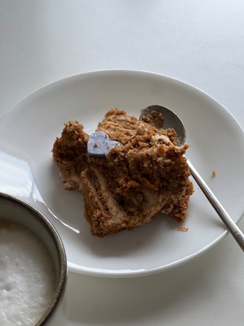 A piece of cake on a plate next to a cup of coffee