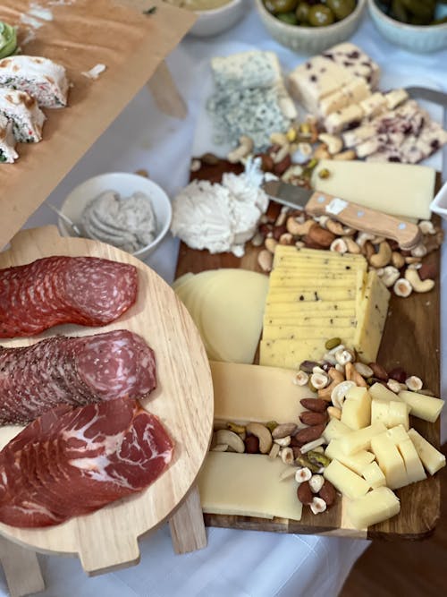 A table with cheese, meats and nuts on it