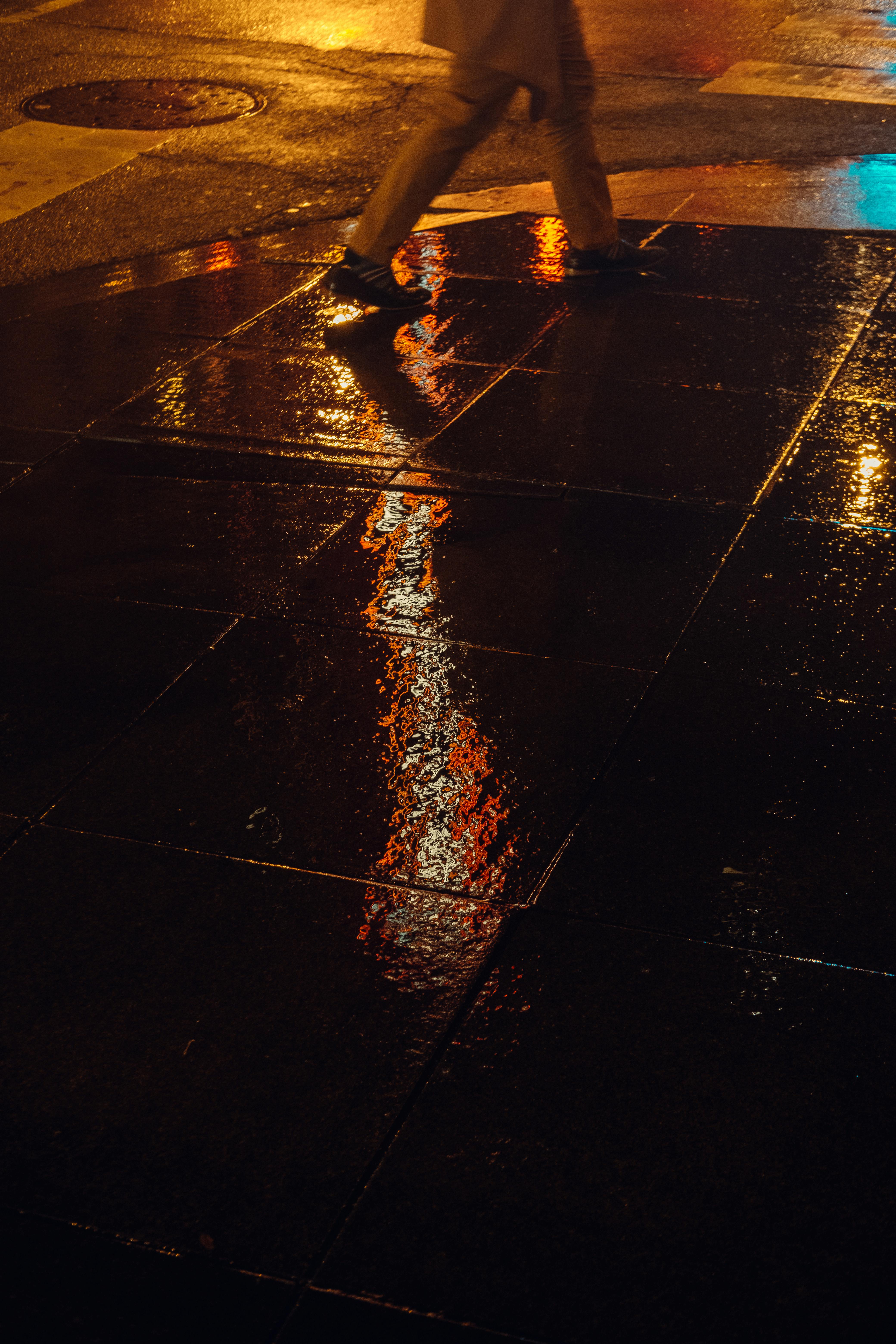 Moody urban scene of a pedestrian crossing a wet street in Chicago at night.