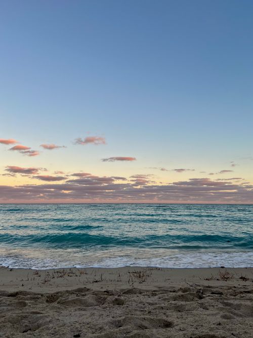 Free Tranquil view of the ocean at sunrise with gentle waves and soft clouds. Stock Photo