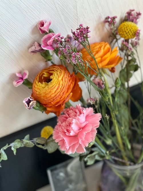 Free A colorful floral arrangement featuring ranunculus and carnations in a modern setting. Stock Photo