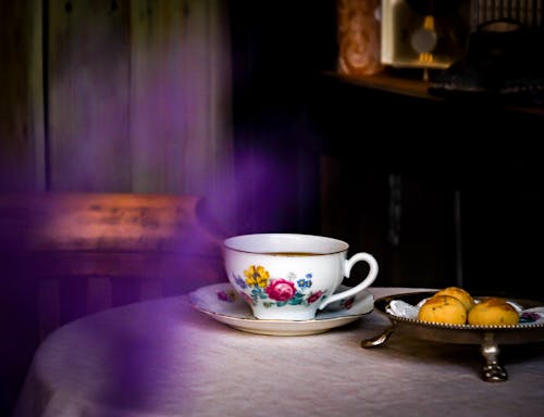 A tea cup and saucer on a table with purple smoke