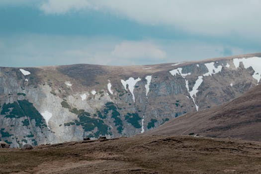 Majestic view of Bucegi Mountains with snow patches during early spring in Romania.