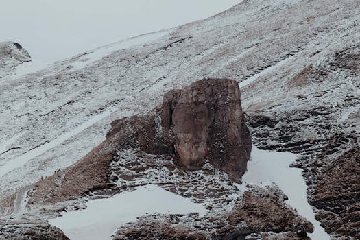 A rugged rock formation in a snowy landscape in Bușteni, Romania.