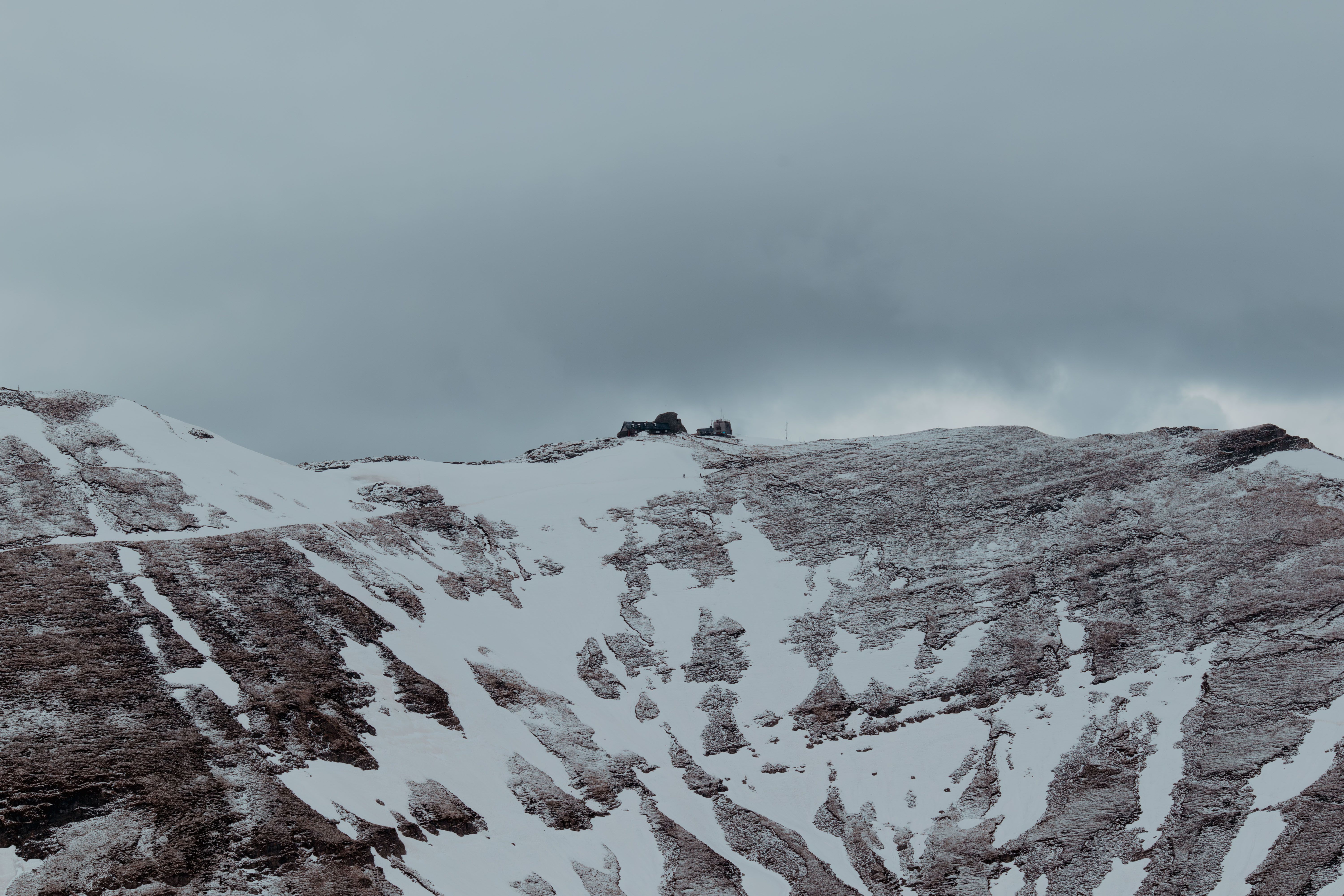 Captivating view of the snow-covered Bucegi Mountains in Bușteni, Romania, under a cloudy sky.