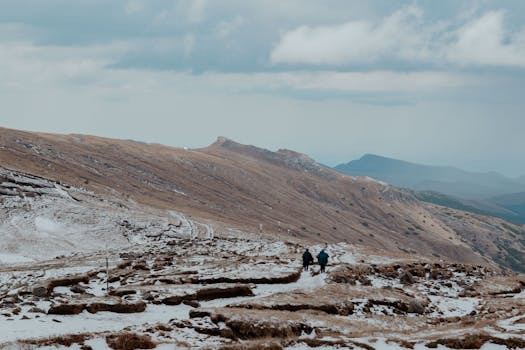 Hikers traverse a snowy trail in the scenic Bucegi Mountains, Romania.