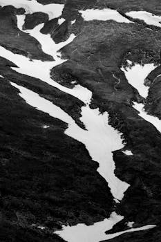 A dramatic black and white photo showing snow patterns on a mountainside in Bușteni, Romania.