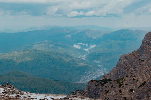 Majestic view of Bucegi Mountains with dramatic clouds and lush green valleys in Romania.