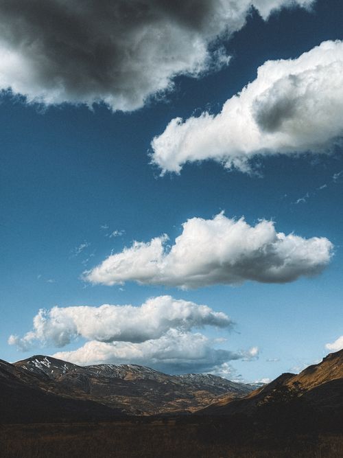 Free Marvel at the dramatic clouds hovering over the rugged mountains in Magallanes, Chile. Stock Photo