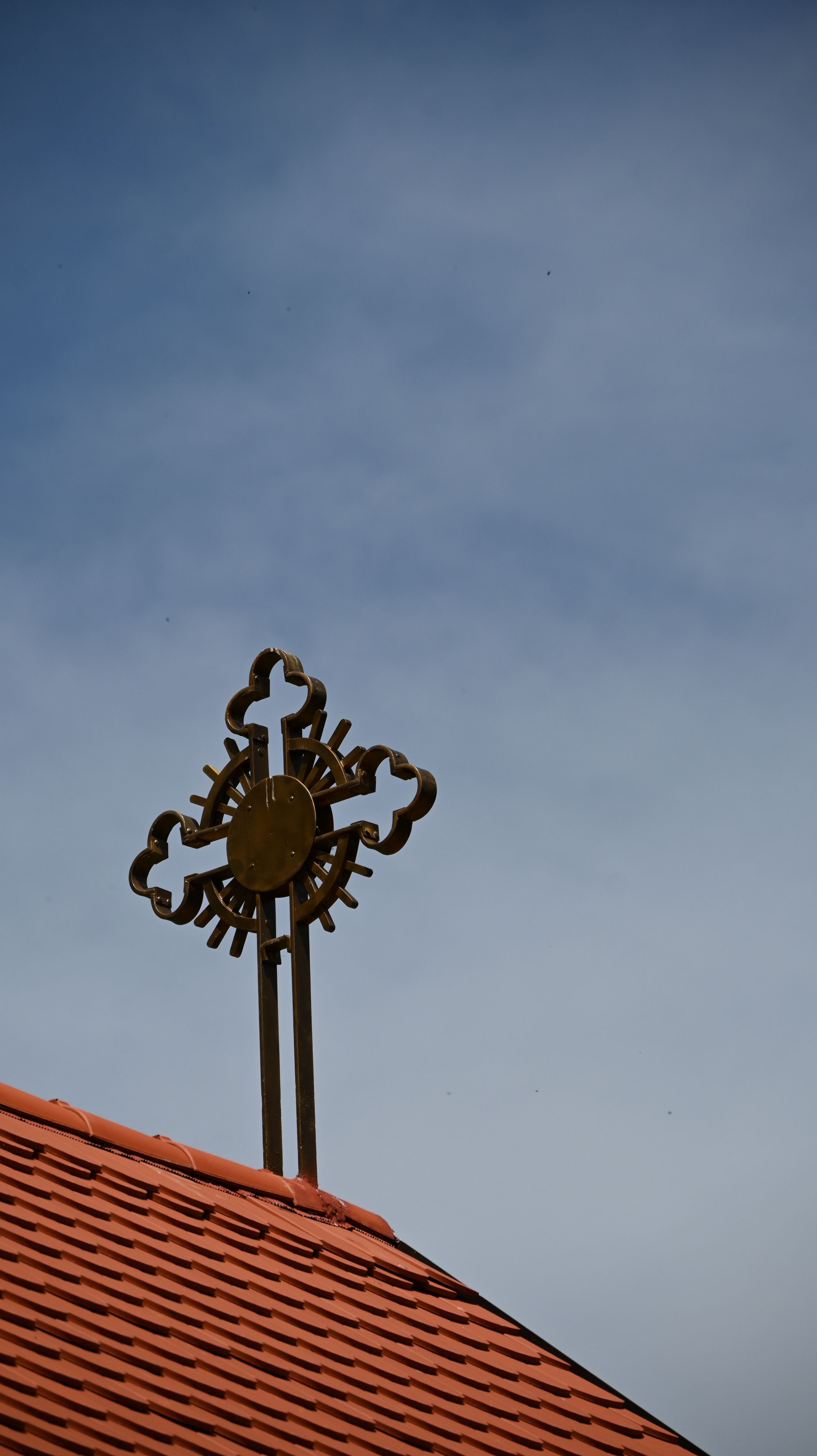 Ornate cross on a church rooftop silhouetted against a clear blue sky in Chicago.