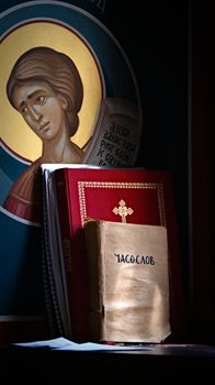 A serene display of religious books and an icon in a dimly lit setting, evoking spiritual reflection.